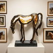 Bronze horse sculpture on a pedestal with framed horse portraits on the wall.