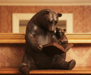 Wooden bear sculpture with a cub reading a book on a wooden surface.