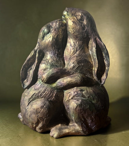 Bronze and gold stroked rabbts embracing
