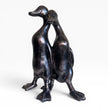 Bronze sculpture of two ducks standing close together on a white background