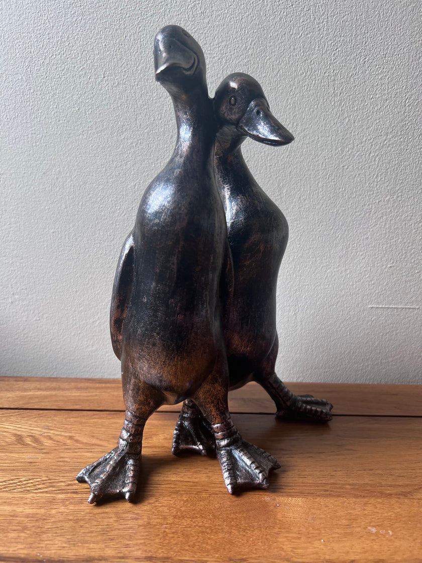 Bronze sculpture of two ducks on a wooden table