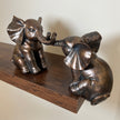 Two antique bronze-effect elephant figurines displayed together on a dark wooden shelf