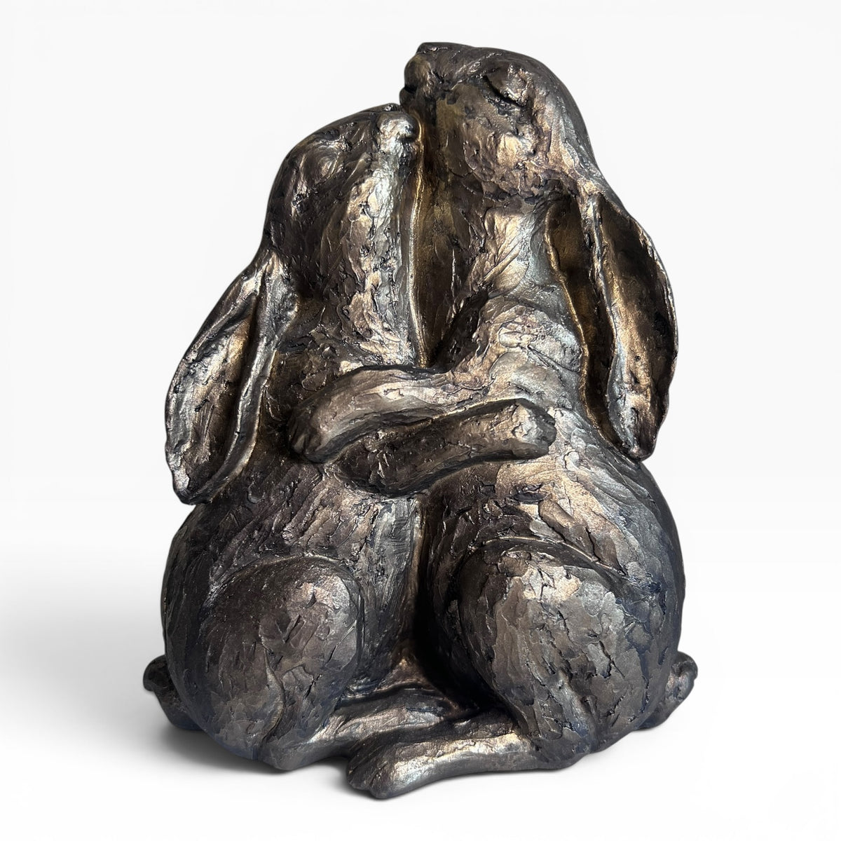 Bronze sculpture of two rabbits embracing on a white background